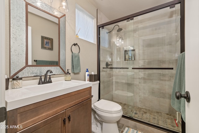 full bath featuring toilet, a shower stall, and vanity