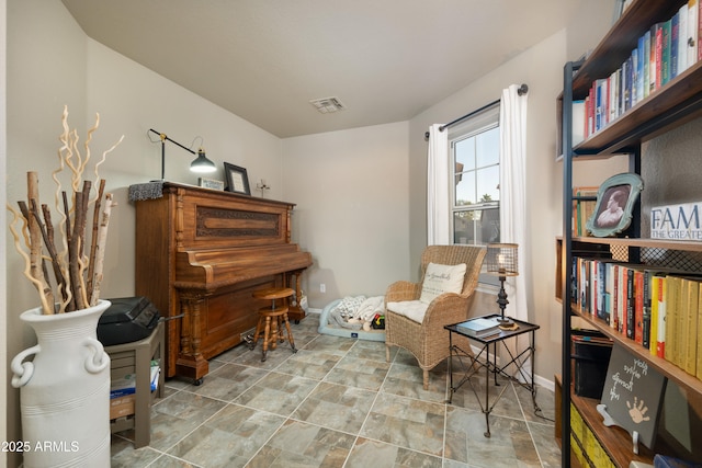 living area featuring stone finish flooring, visible vents, and baseboards