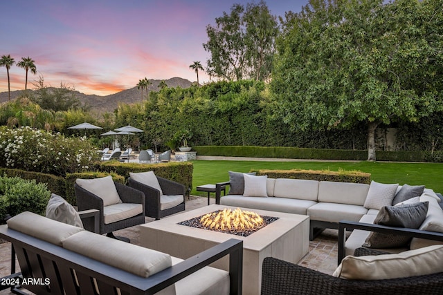 patio terrace at dusk with a mountain view, an outdoor living space with a fire pit, and a yard