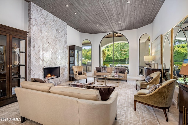 living room with a fireplace, wooden ceiling, and plenty of natural light