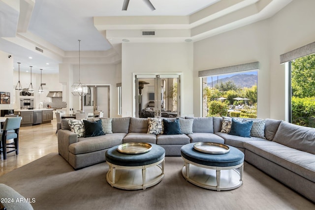 living room featuring a high ceiling, ceiling fan, and a raised ceiling