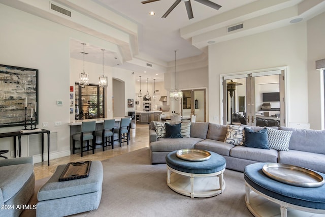 tiled living room with a towering ceiling and ceiling fan with notable chandelier