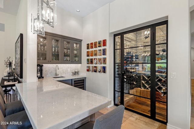 wine room with a high ceiling, beverage cooler, light tile patterned flooring, and indoor wet bar