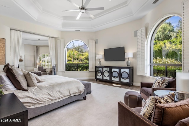 bedroom with crown molding, hardwood / wood-style flooring, ceiling fan, and a tray ceiling