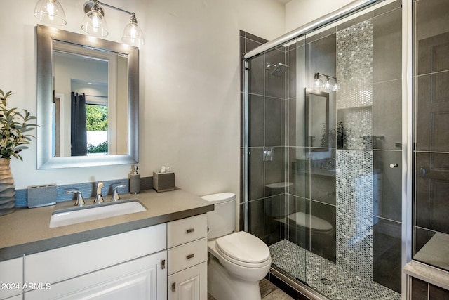 bathroom with a shower with shower door, vanity, and toilet