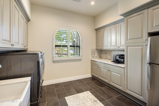 clothes washing area with dark tile patterned flooring, cabinets, and washer and dryer