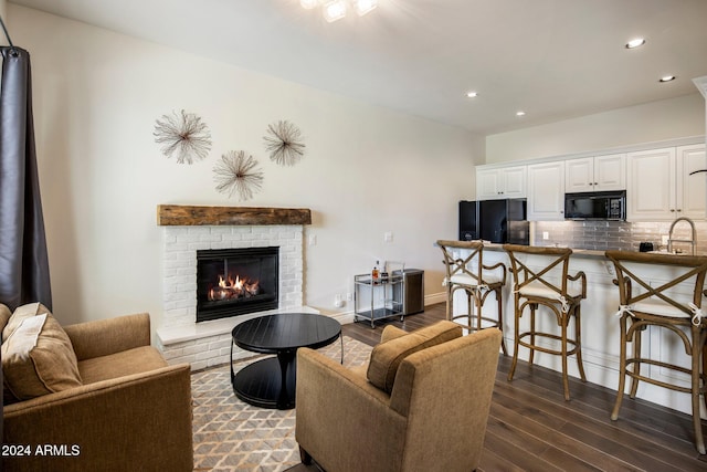 living room with dark hardwood / wood-style flooring, sink, and a fireplace