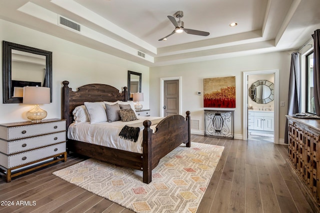 bedroom with sink, ceiling fan, a tray ceiling, connected bathroom, and dark hardwood / wood-style flooring