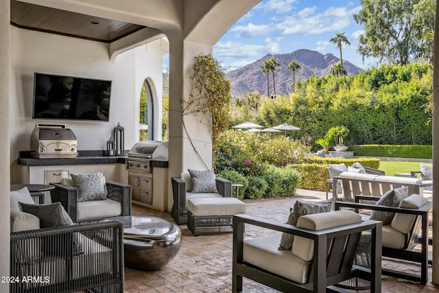 view of patio / terrace featuring ceiling fan, exterior kitchen, area for grilling, outdoor lounge area, and a mountain view