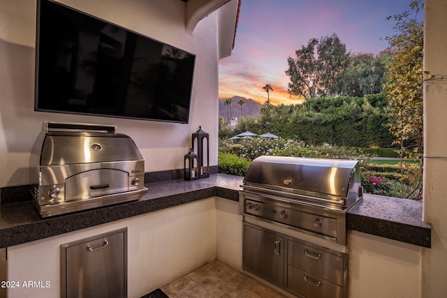 patio terrace at dusk with an outdoor kitchen and grilling area