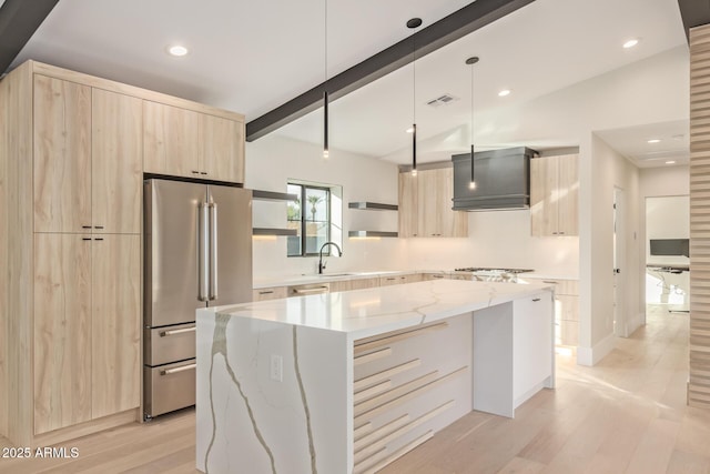 kitchen featuring light brown cabinets, a sink, freestanding refrigerator, modern cabinets, and custom range hood