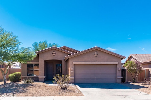 mediterranean / spanish house with driveway, fence, an attached garage, and stucco siding