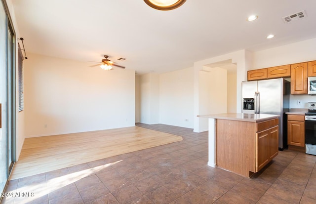 kitchen featuring a center island, stainless steel appliances, light countertops, visible vents, and a ceiling fan