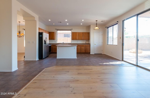 kitchen featuring stainless steel fridge with ice dispenser, a kitchen island, open floor plan, a chandelier, and recessed lighting