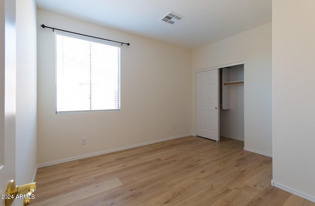 unfurnished bedroom featuring light wood finished floors, a closet, visible vents, and baseboards