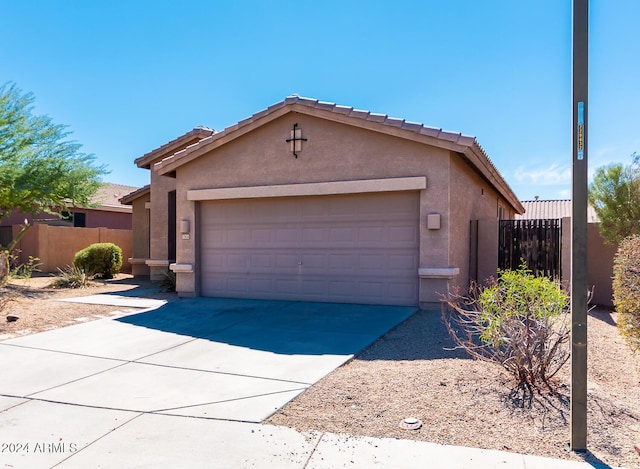 view of front of home featuring driveway, an attached garage, fence, and stucco siding