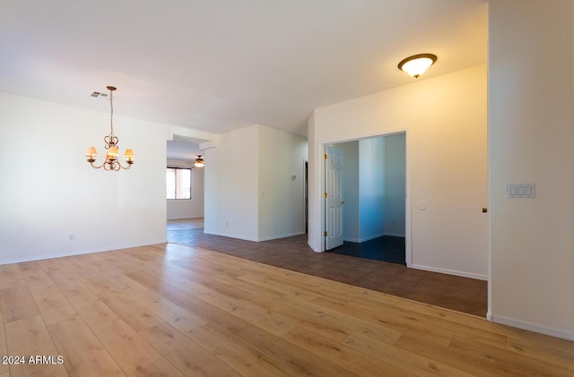 empty room with light wood-type flooring, visible vents, baseboards, and an inviting chandelier