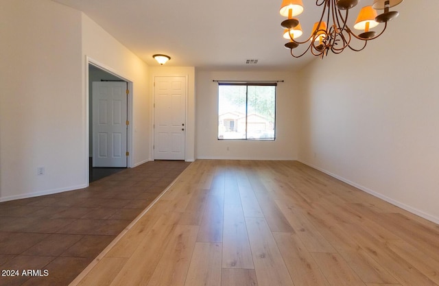 interior space featuring visible vents, a notable chandelier, baseboards, and wood finished floors