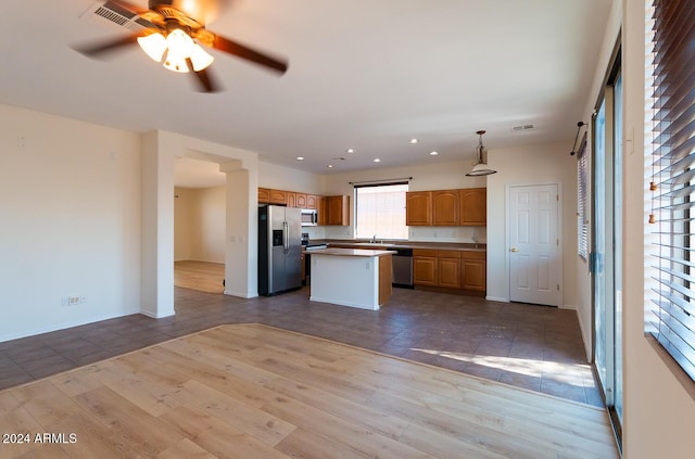 kitchen with visible vents, a kitchen island, appliances with stainless steel finishes, wood finished floors, and a sink