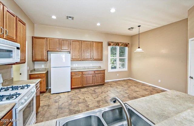 kitchen with hanging light fixtures, sink, and white appliances