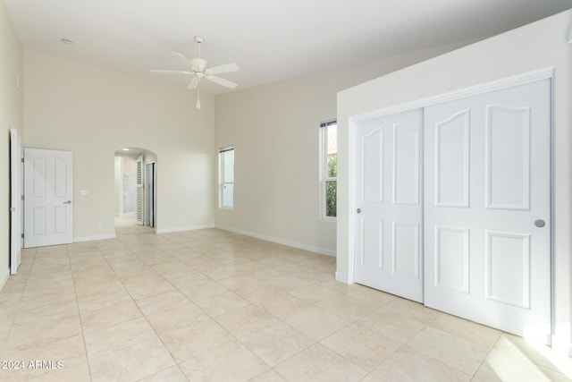 unfurnished bedroom with light tile patterned floors, a closet, and ceiling fan