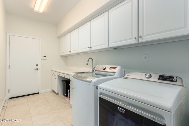 laundry area with washer and clothes dryer, cabinets, light tile patterned floors, and sink