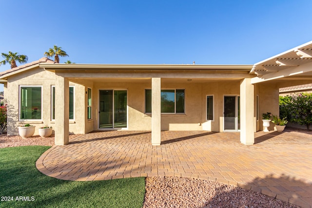 rear view of property featuring a pergola and a patio