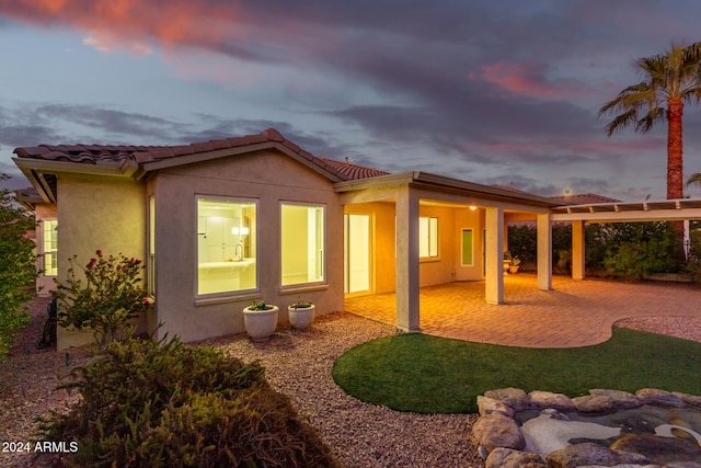 back house at dusk with a patio area