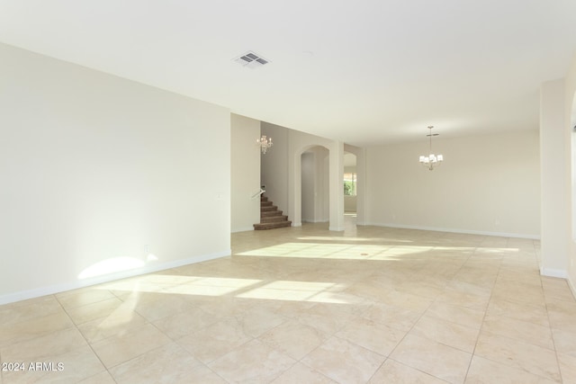 spare room with an inviting chandelier and light tile patterned floors