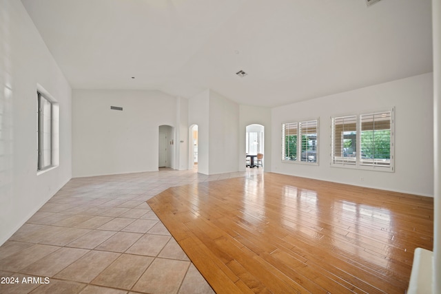 unfurnished living room with light wood-type flooring and vaulted ceiling