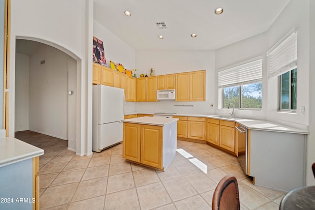 kitchen with lofted ceiling, white appliances, light brown cabinetry, and a kitchen island