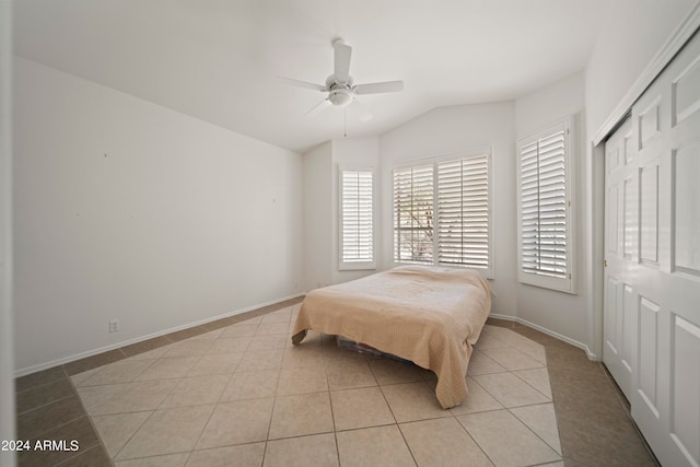 bedroom with lofted ceiling, light tile patterned flooring, ceiling fan, and a closet