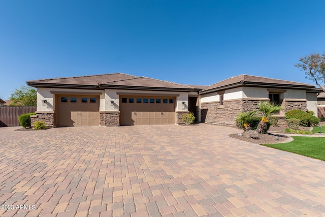 prairie-style house featuring stucco siding, stone siding, an attached garage, and decorative driveway
