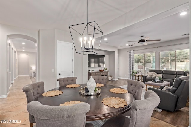 dining space featuring visible vents, ceiling fan with notable chandelier, arched walkways, light tile patterned floors, and baseboards