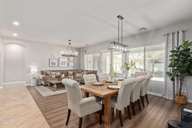 dining room with light wood-style flooring, recessed lighting, arched walkways, and visible vents