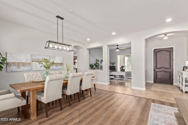 dining space with arched walkways, recessed lighting, and light wood-type flooring