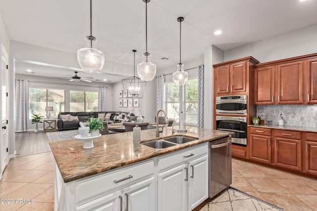 kitchen with decorative backsplash, appliances with stainless steel finishes, light stone countertops, and a sink