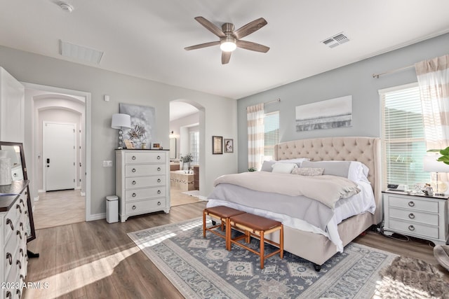 bedroom featuring wood finished floors, visible vents, and arched walkways