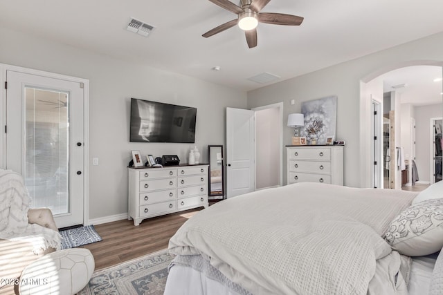 bedroom with wood finished floors, visible vents, baseboards, arched walkways, and ceiling fan