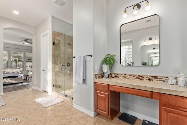 ensuite bathroom featuring a shower stall, a ceiling fan, visible vents, and backsplash