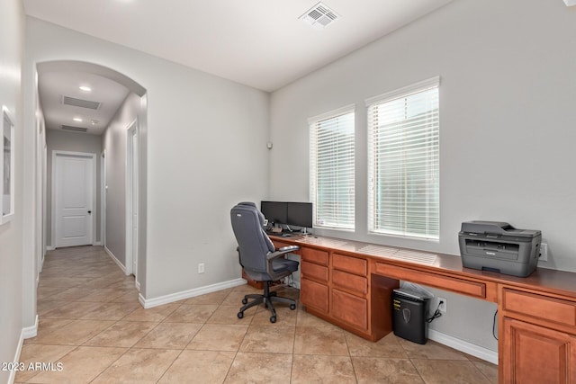 office featuring arched walkways, visible vents, baseboards, and light tile patterned floors