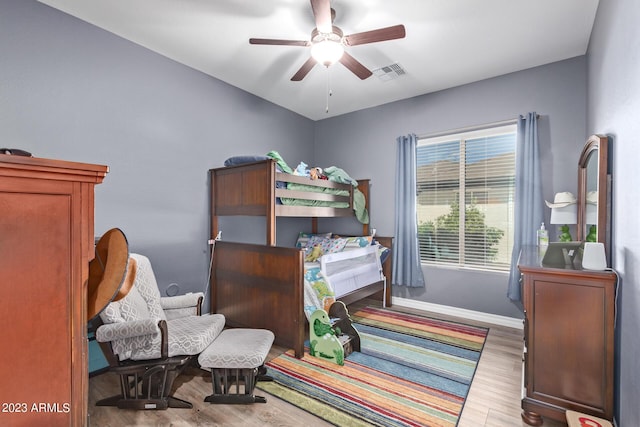 bedroom with a ceiling fan, wood finished floors, visible vents, and baseboards