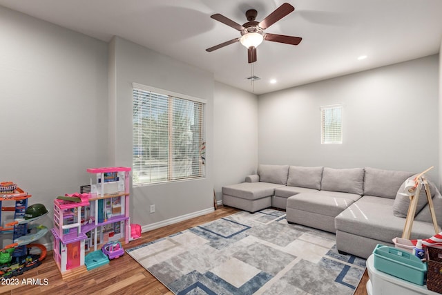 living area featuring a healthy amount of sunlight, baseboards, a ceiling fan, and wood finished floors