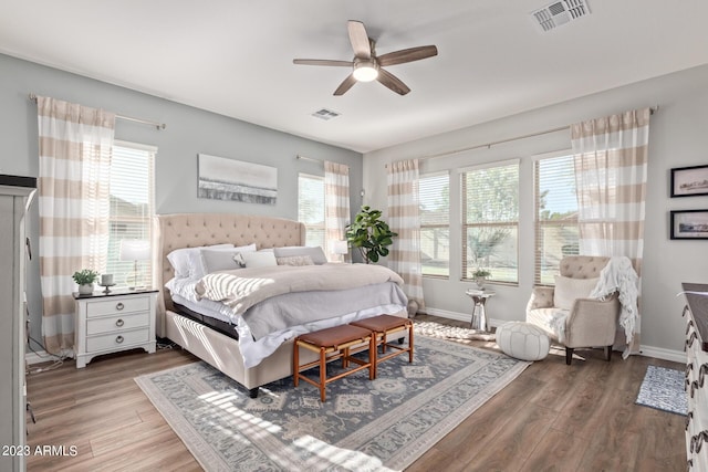 bedroom with ceiling fan, visible vents, baseboards, and wood finished floors