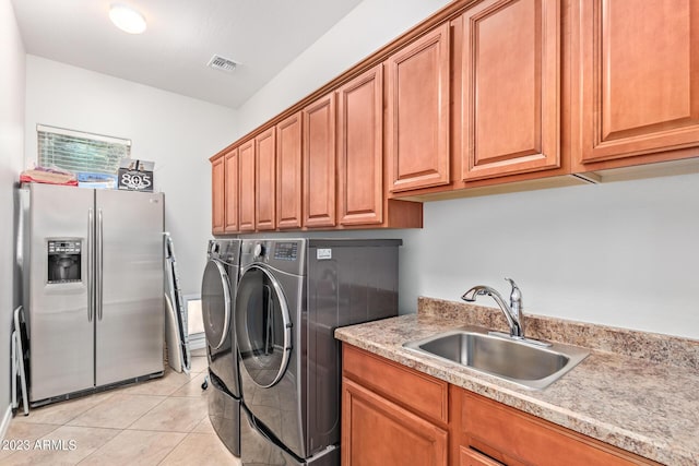 laundry room featuring visible vents, washing machine and clothes dryer, light tile patterned flooring, cabinet space, and a sink