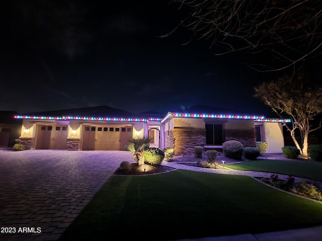 view of front of home featuring stucco siding, stone siding, an attached garage, and decorative driveway