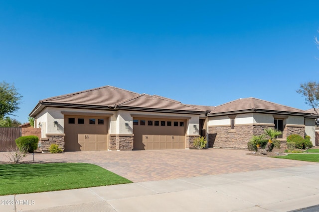 prairie-style house with stone siding, stucco siding, a tiled roof, and a garage