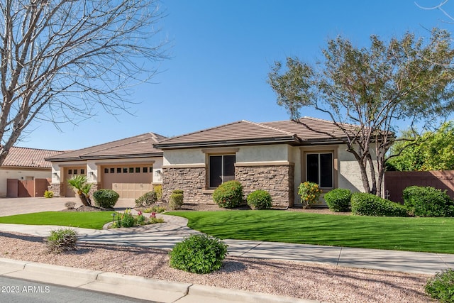 prairie-style home with an attached garage, fence, stone siding, and stucco siding