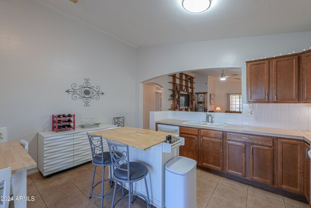 kitchen with a breakfast bar, a center island, sink, and wooden counters