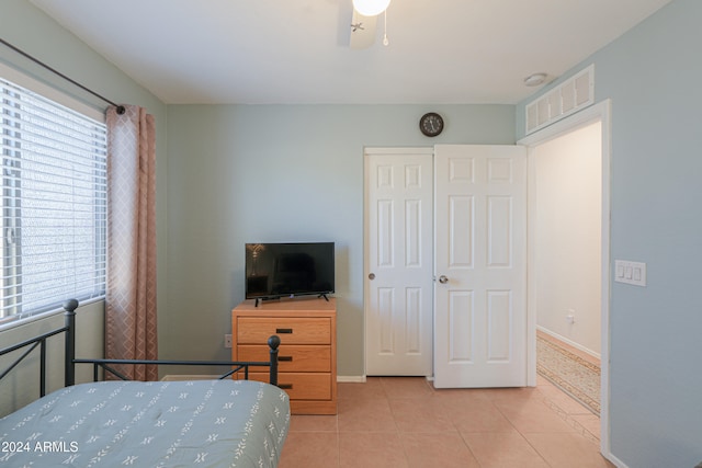 tiled bedroom with ceiling fan and a closet